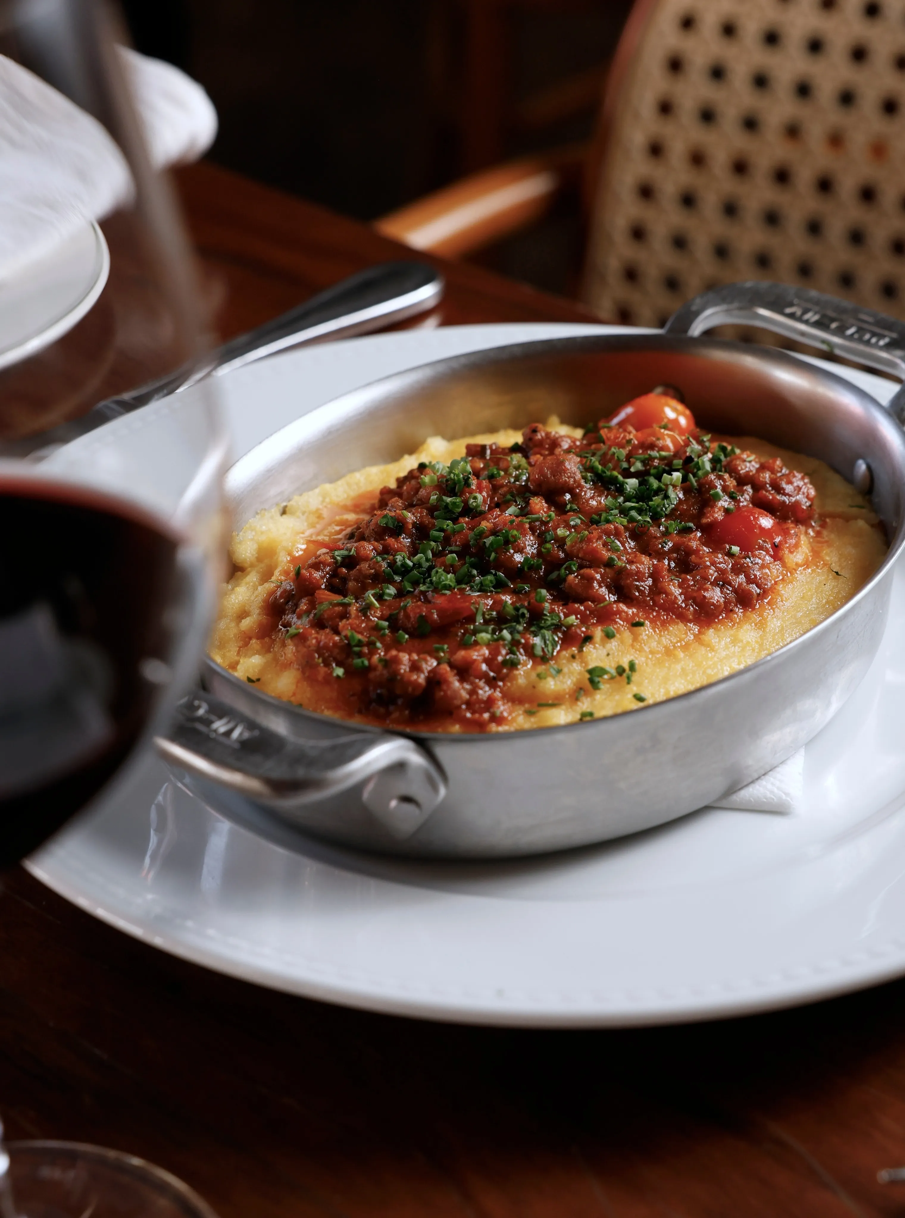 Prato de polenta com molho servido em uma panela sobre mesa de restaurante.