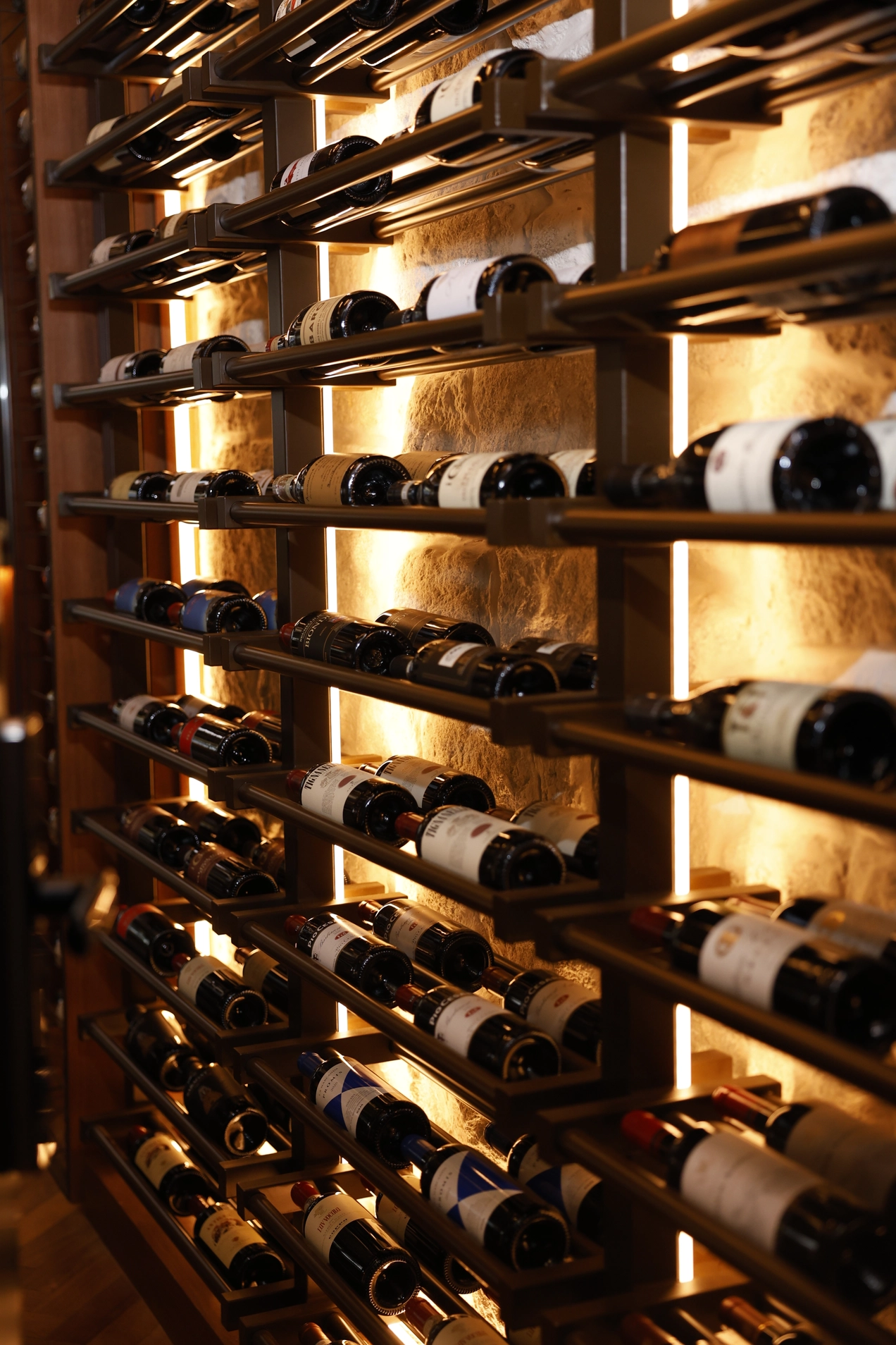 Adega climatizada com vinhos acomodados em prateleiras iluminadas.